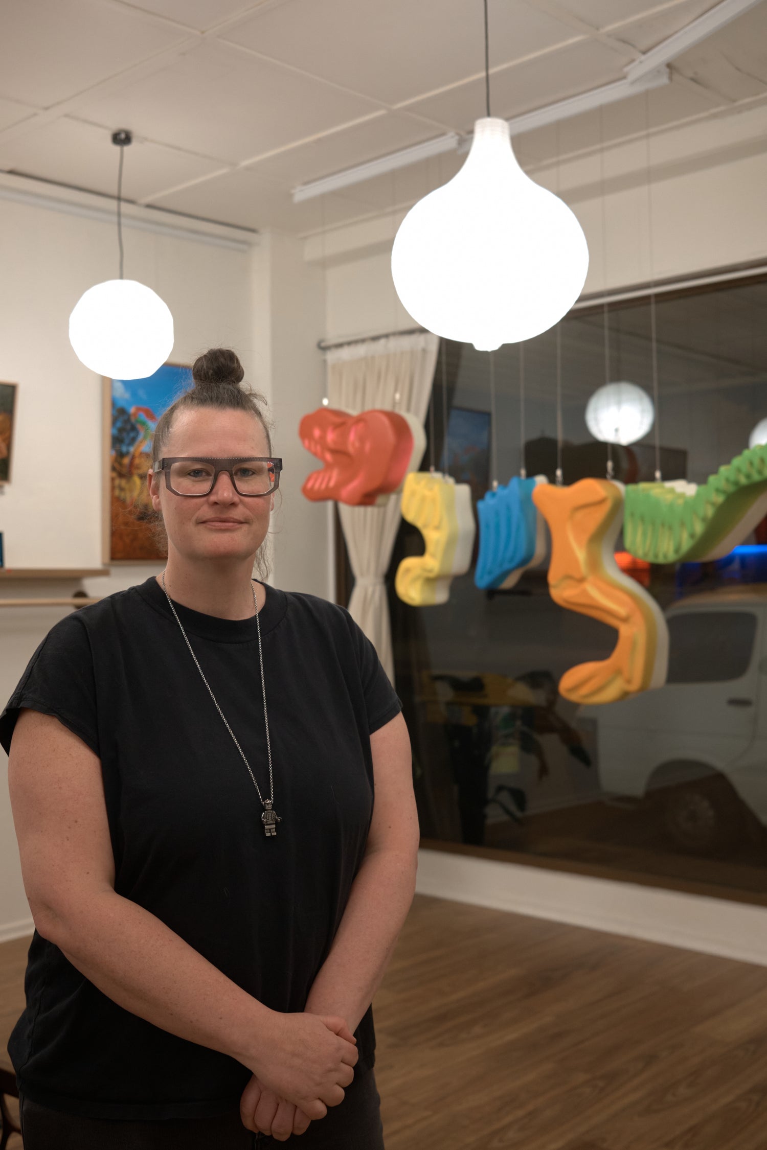 Sally Hastings the artist posing with her giant gummy t-rex skeleton sculpture pop art exhibition