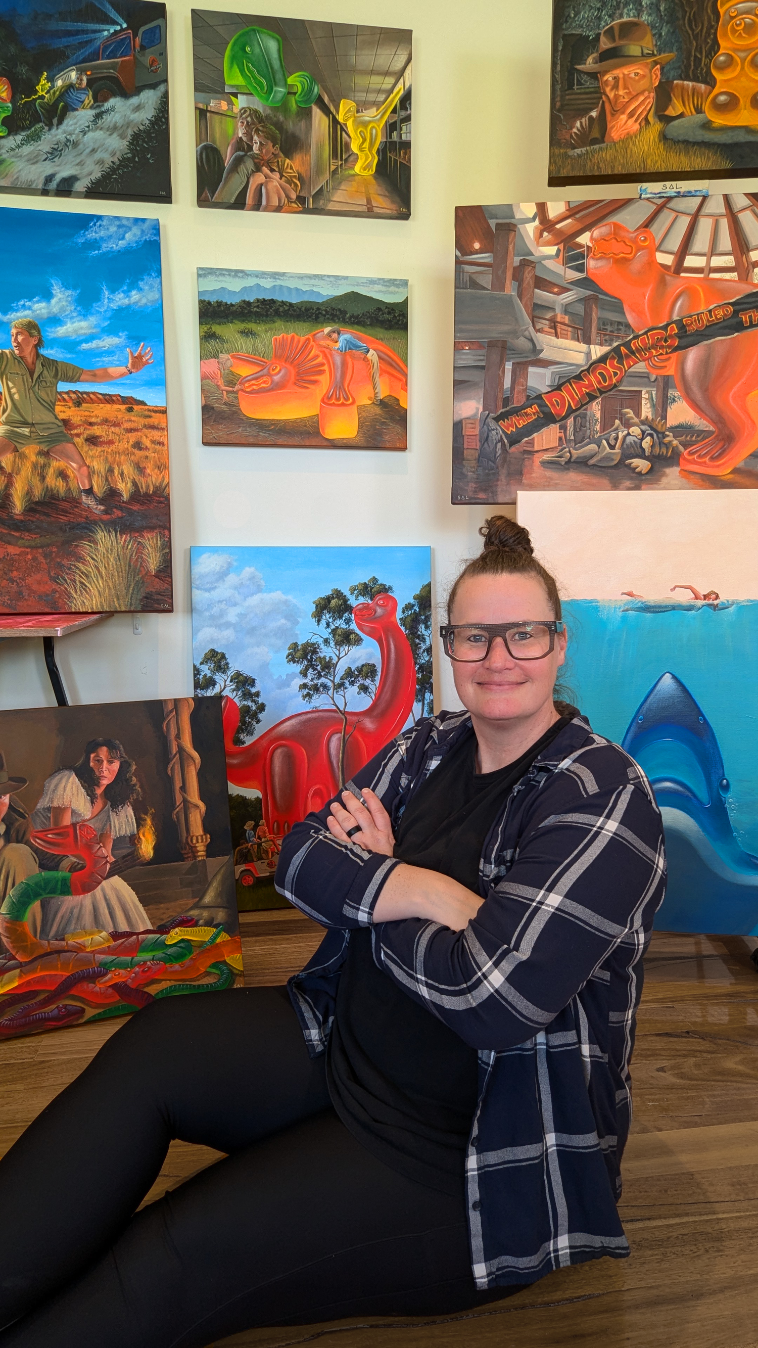 Sally Hastings the artist posing in front of her gummy dinosaur original paintings
